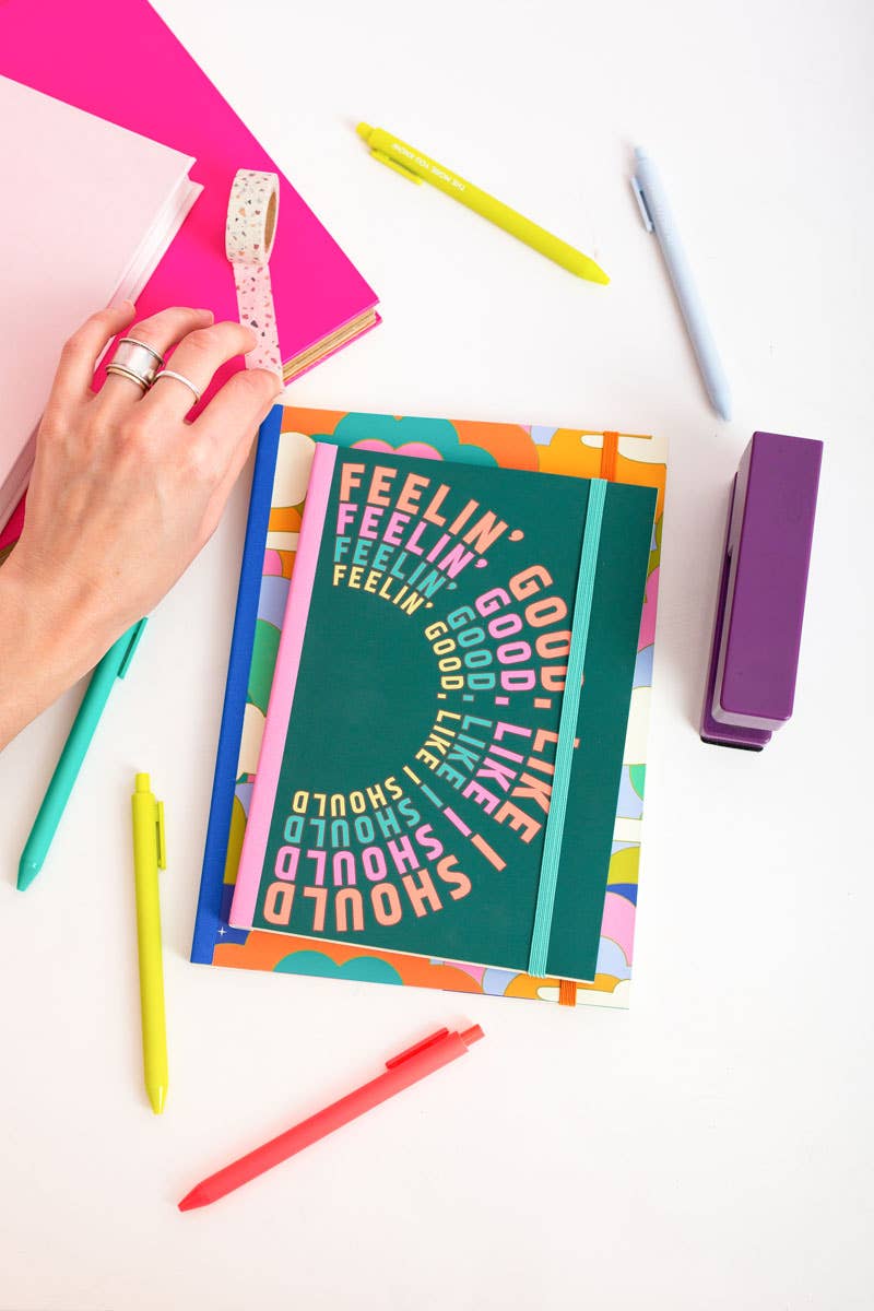 Colorful notebook with motivational text on a white surface with stationery items.