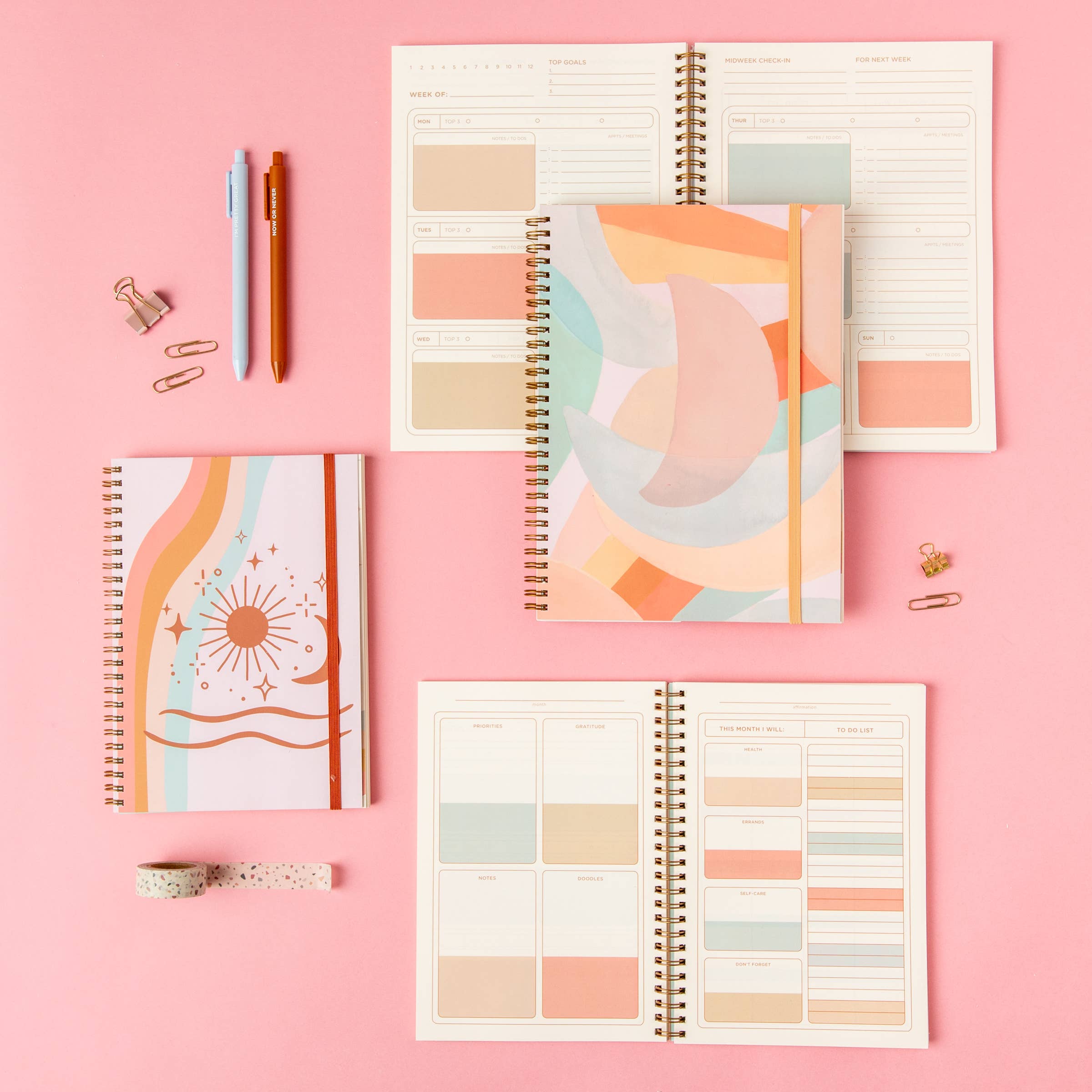 Colorful planners and stationery items on a pink background