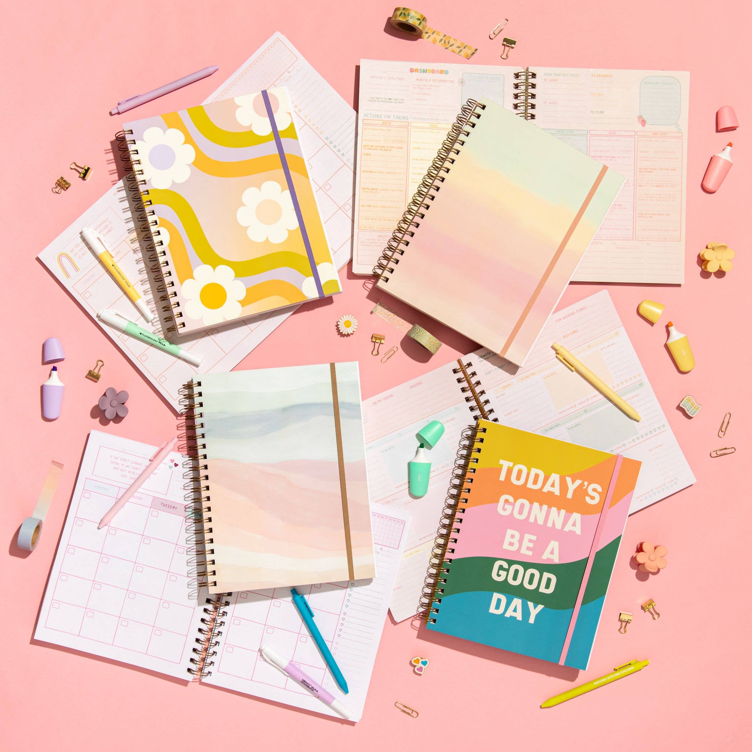 Collection of colorful planners and notebooks on a pink background