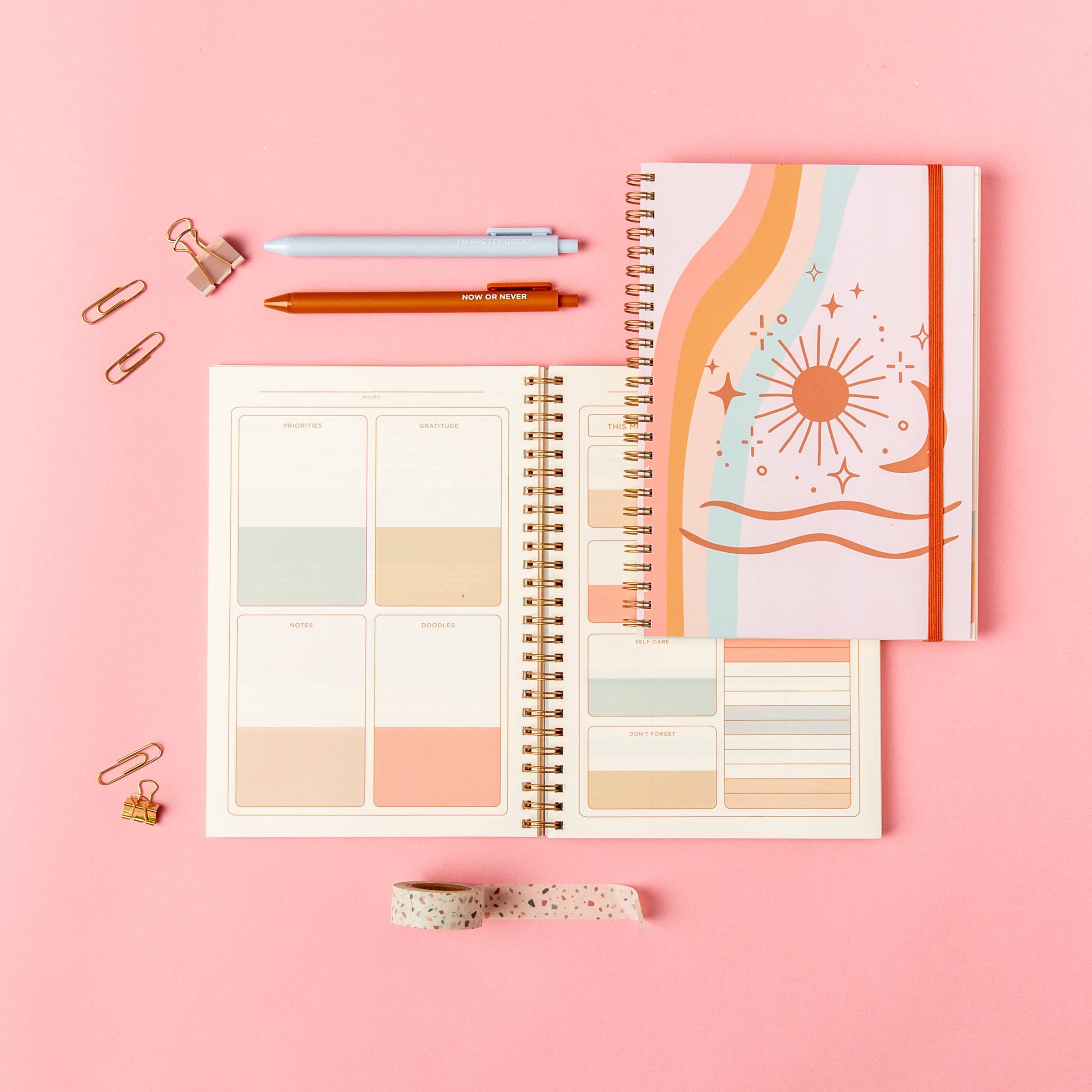 Open spiral-bound planner with colorful design on a pink background