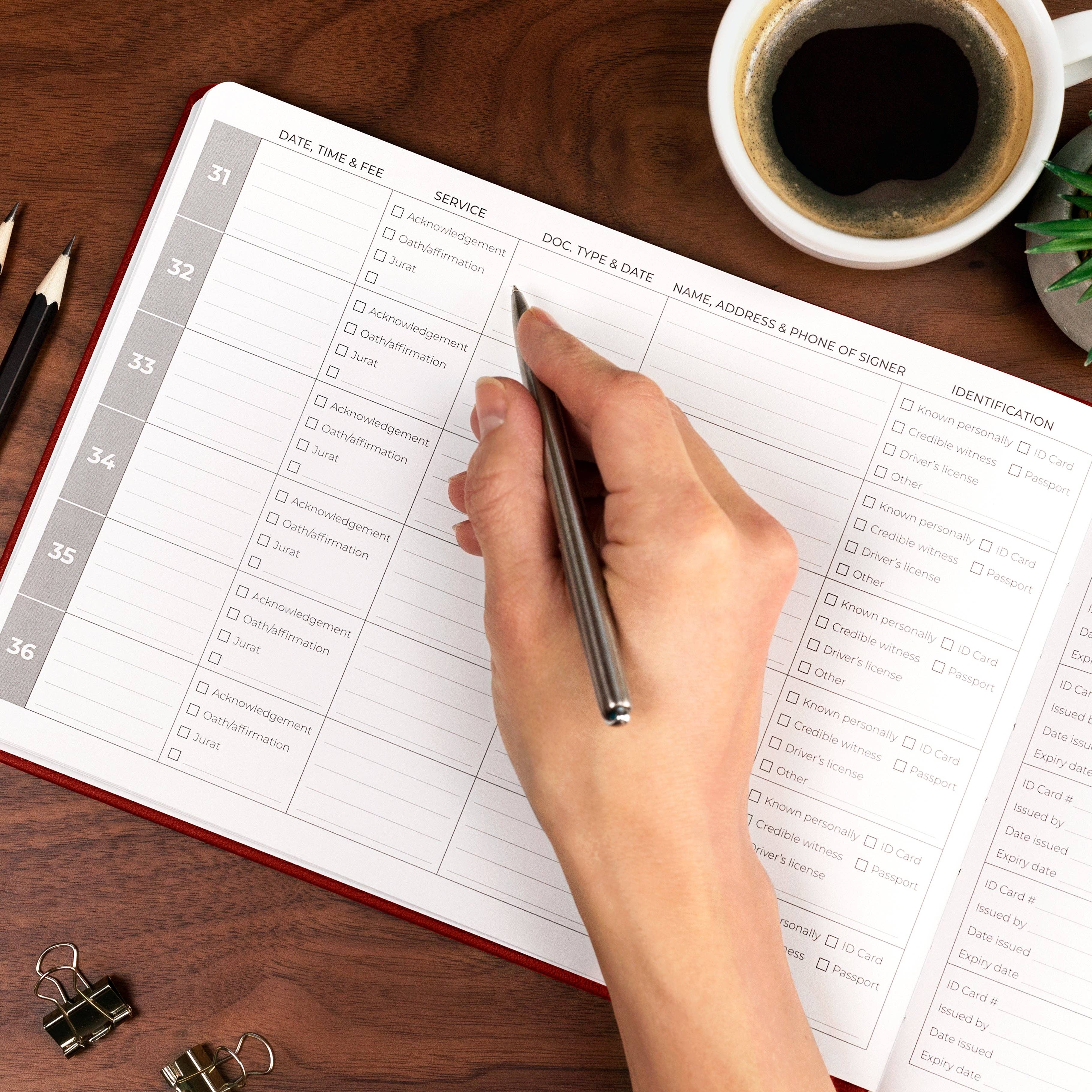 Hand filling out a form on a desk with a cup of coffee and office supplies.