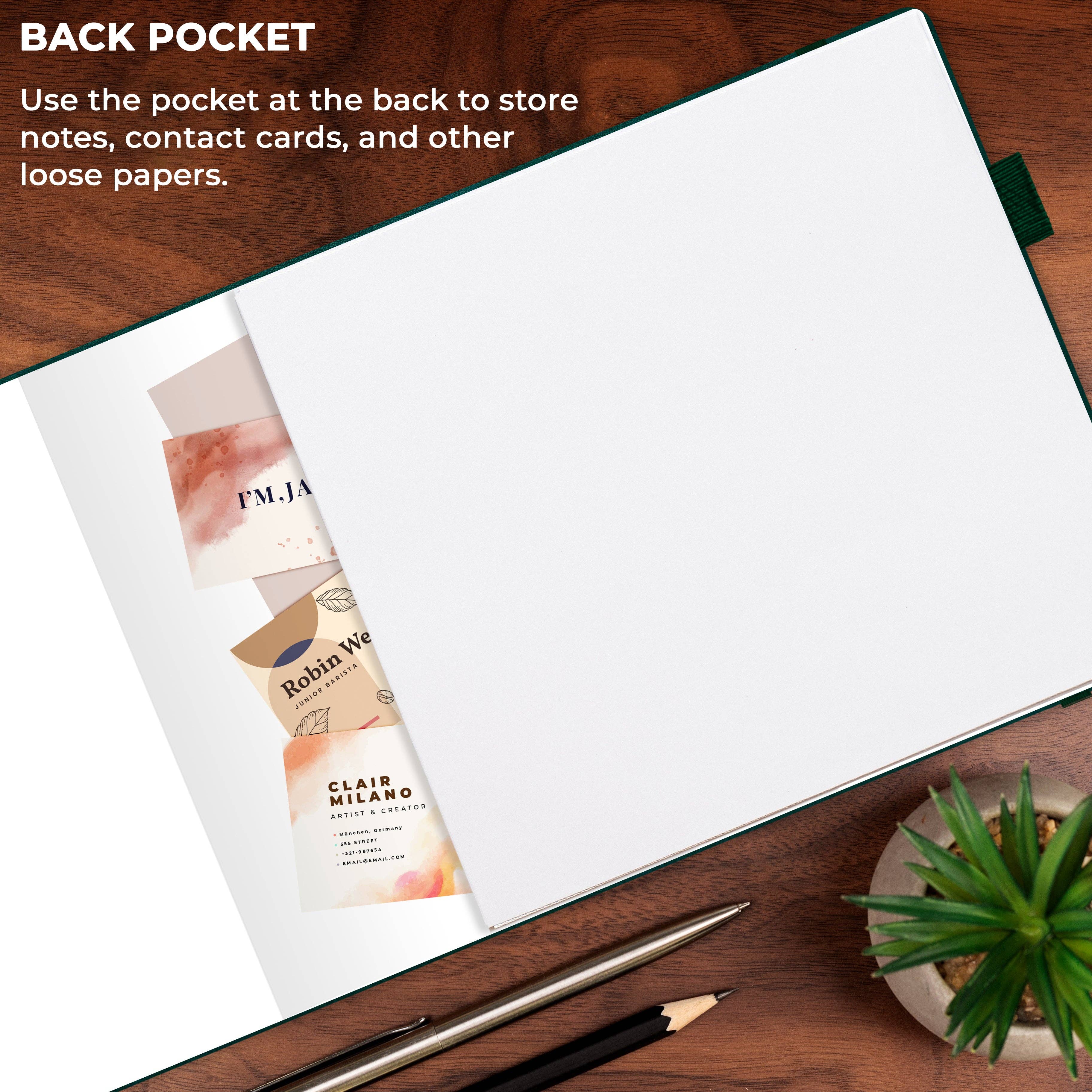 An open notebook or journal laid on a wooden desk, showing a large blank white page on the front and a dark green pocket along the back edge. Text in the upper left explains using the back pocket for notes, contact cards, and loose papers.