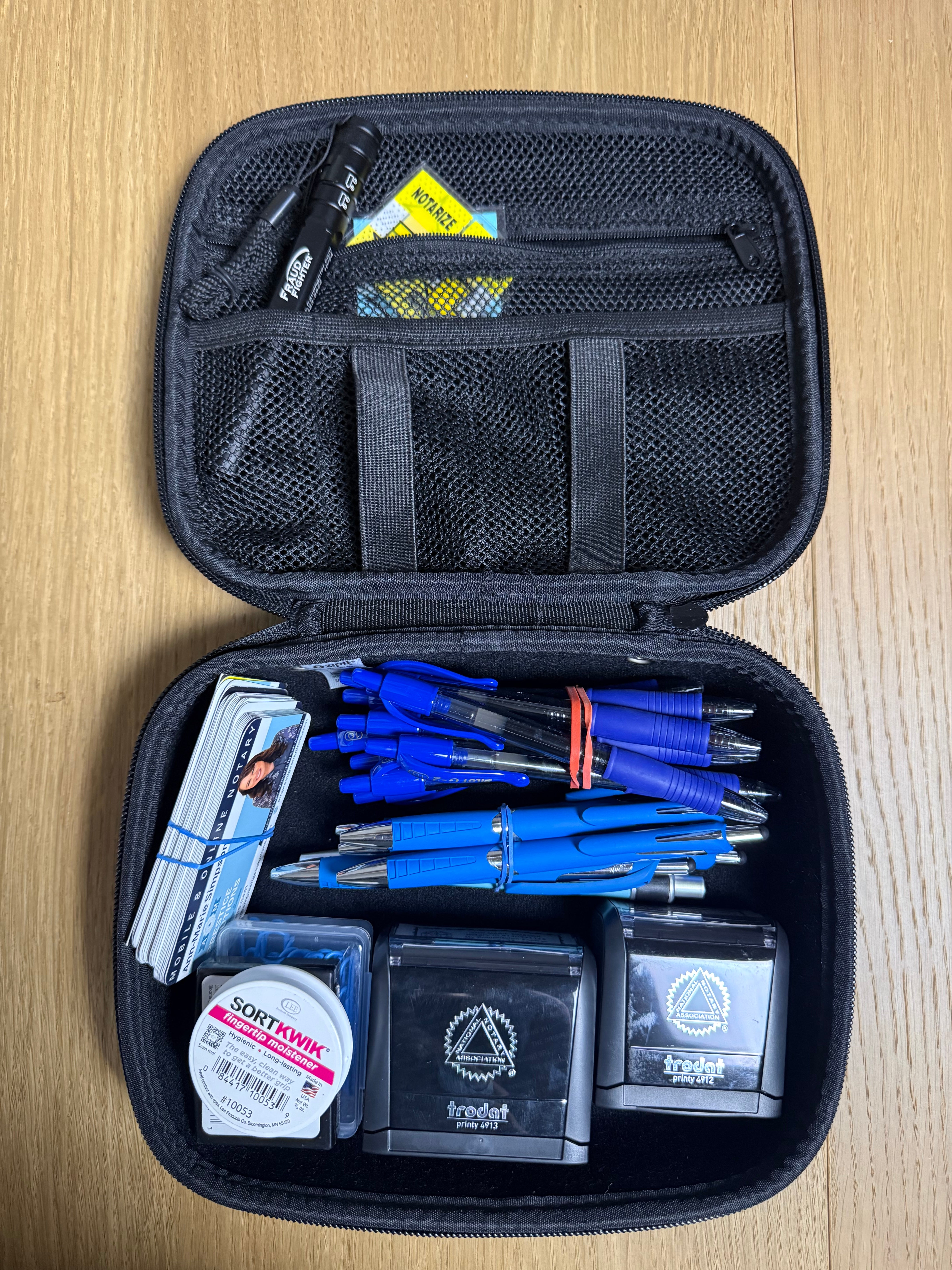 Black carrying case open on a wooden surface with blue and silver items inside