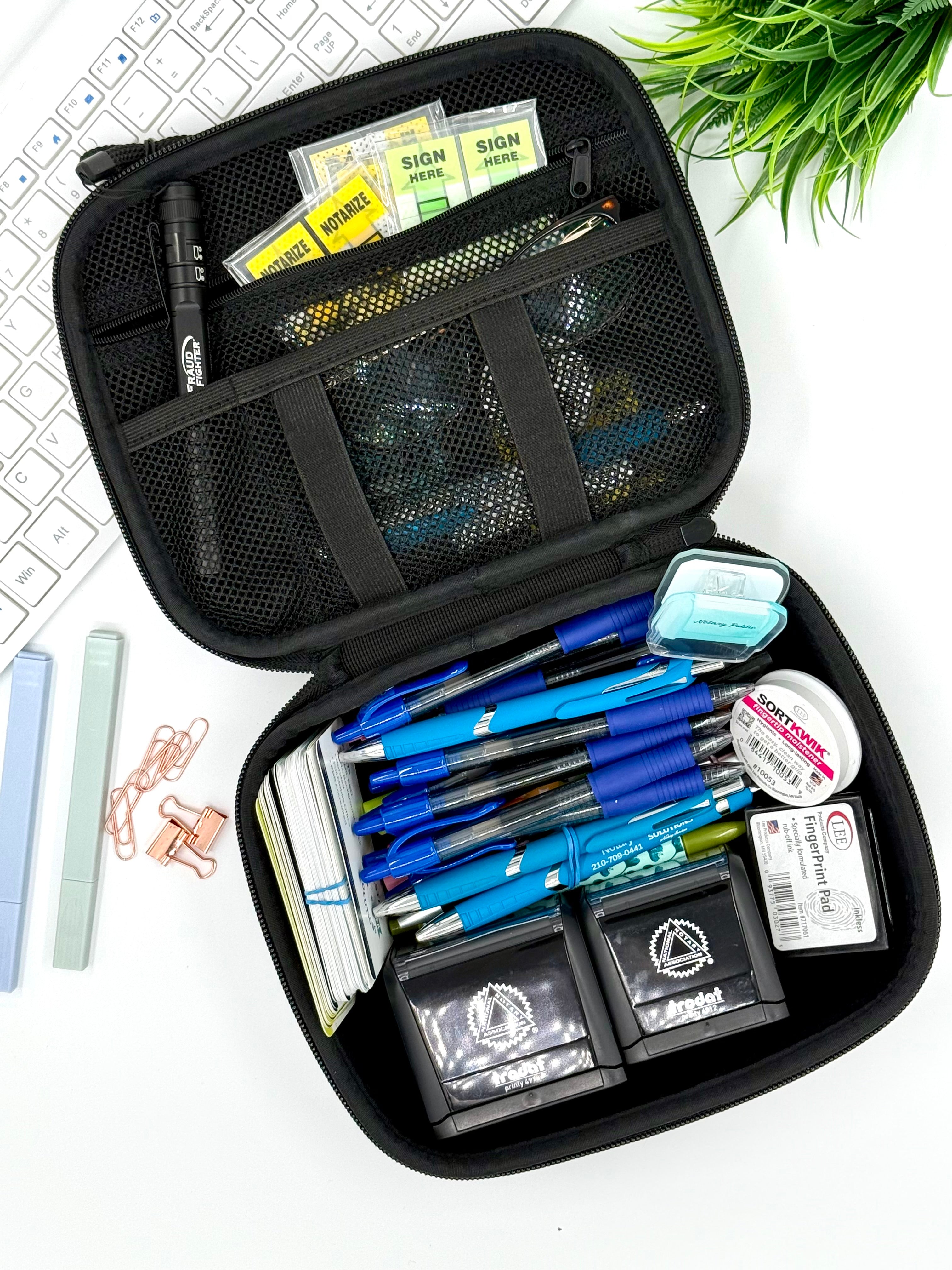 Black organizer case filled with stationery items on a white background