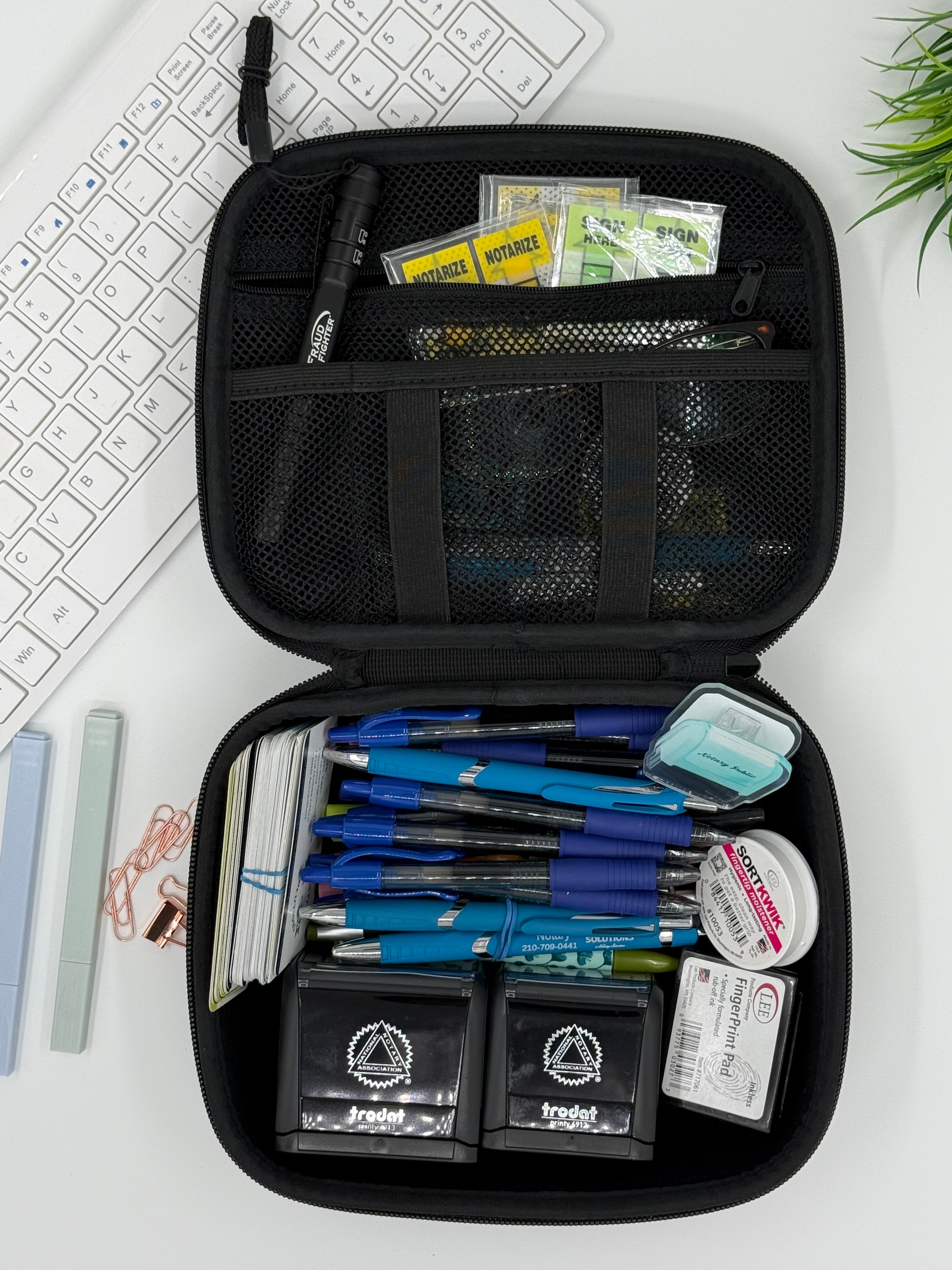 Open black travel case with stationery items on a white surface