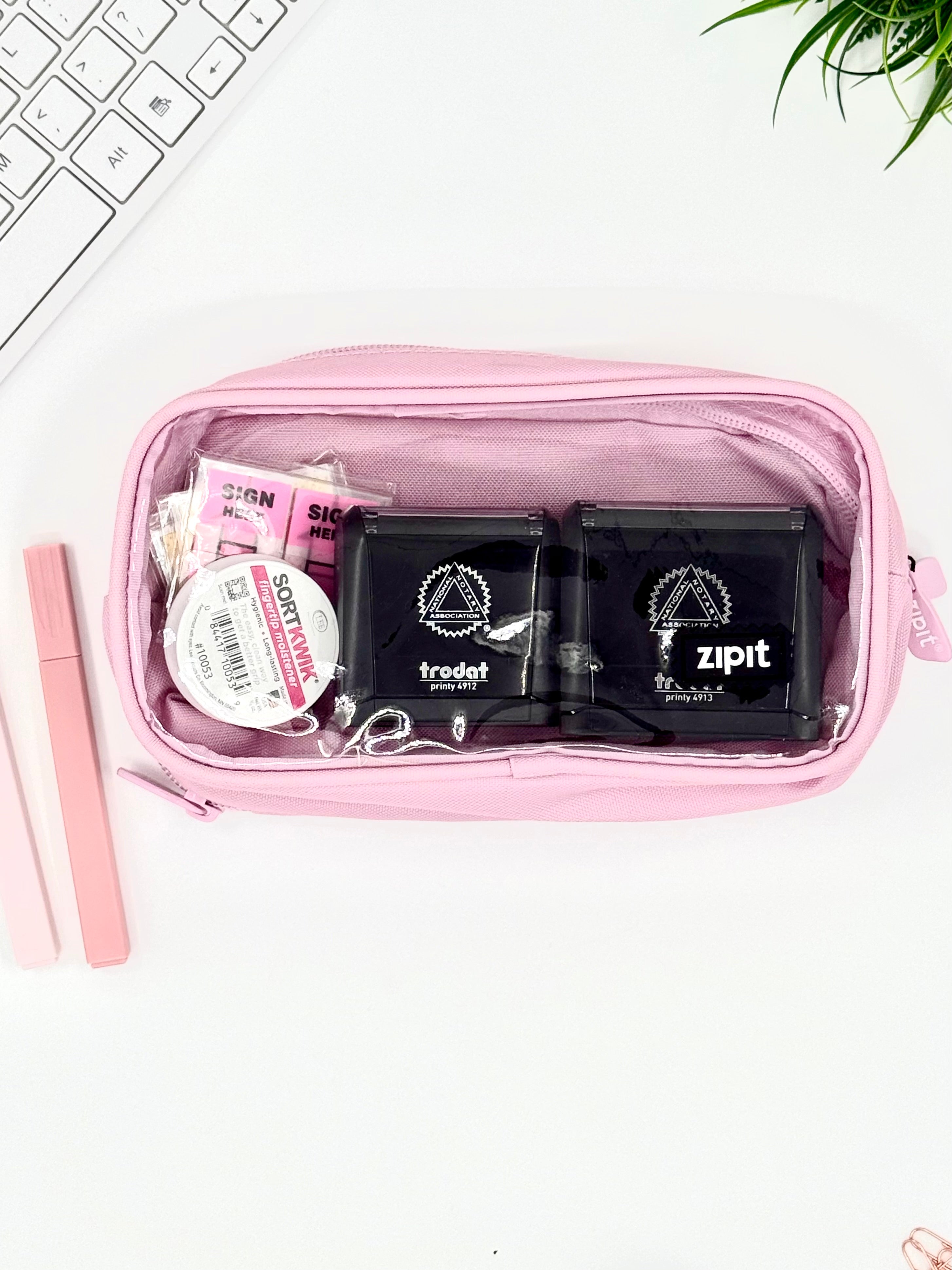 Pink travel pouch with toiletries on a white surface