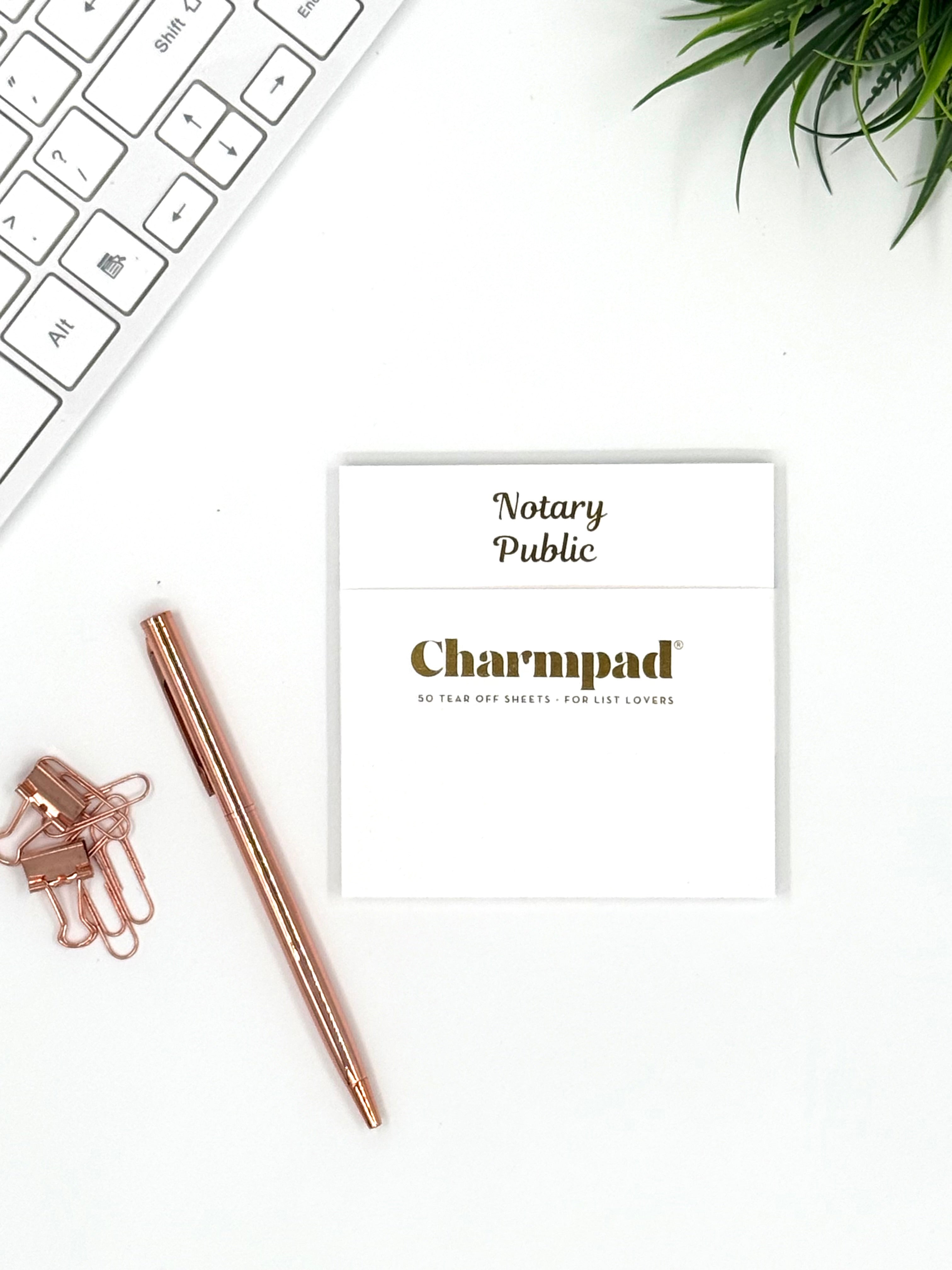 Notary Public Charmpad card on a desk with a pen and keyboard.