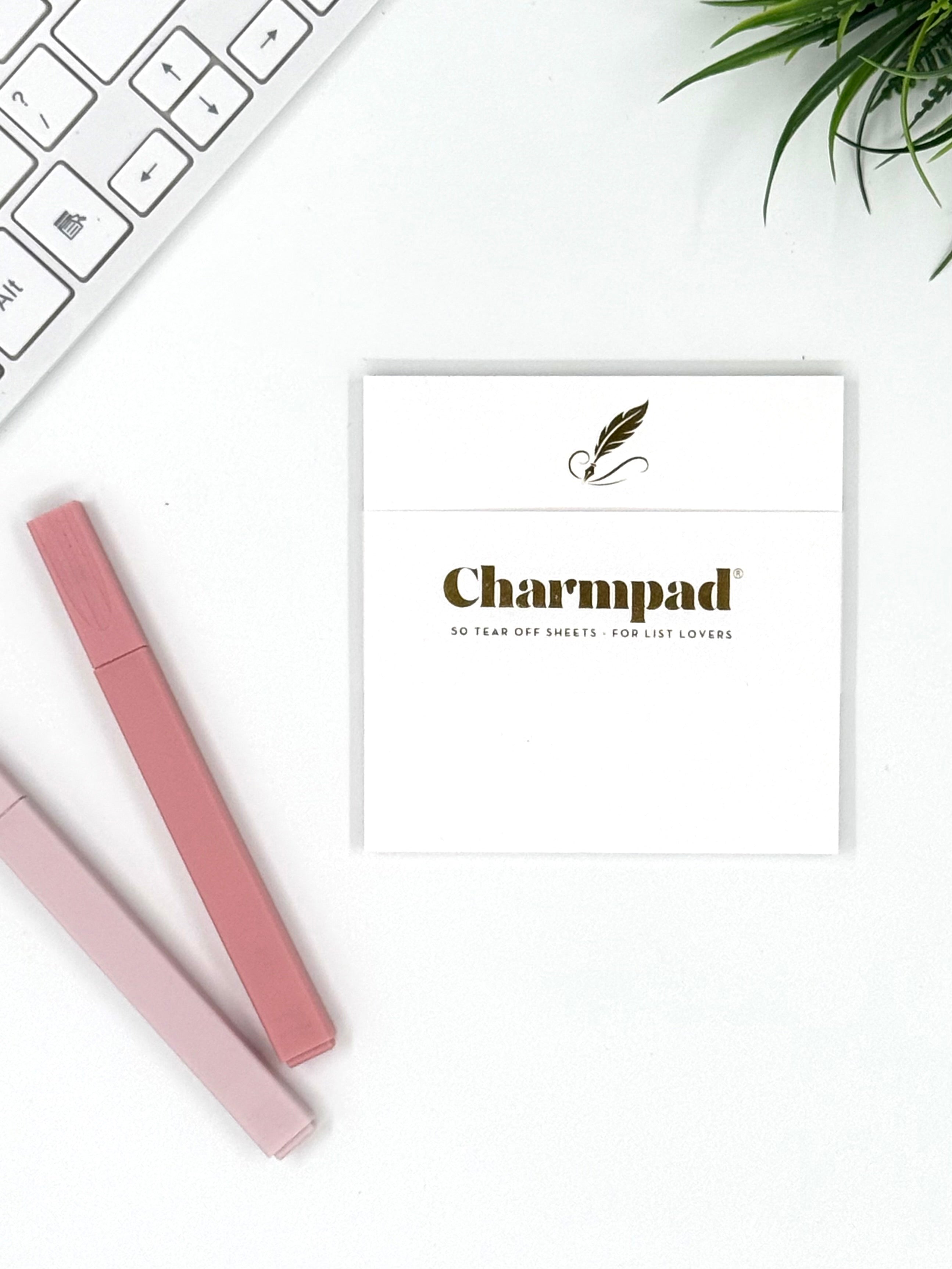 Pink Charmpad product on a white background with keyboard and plant