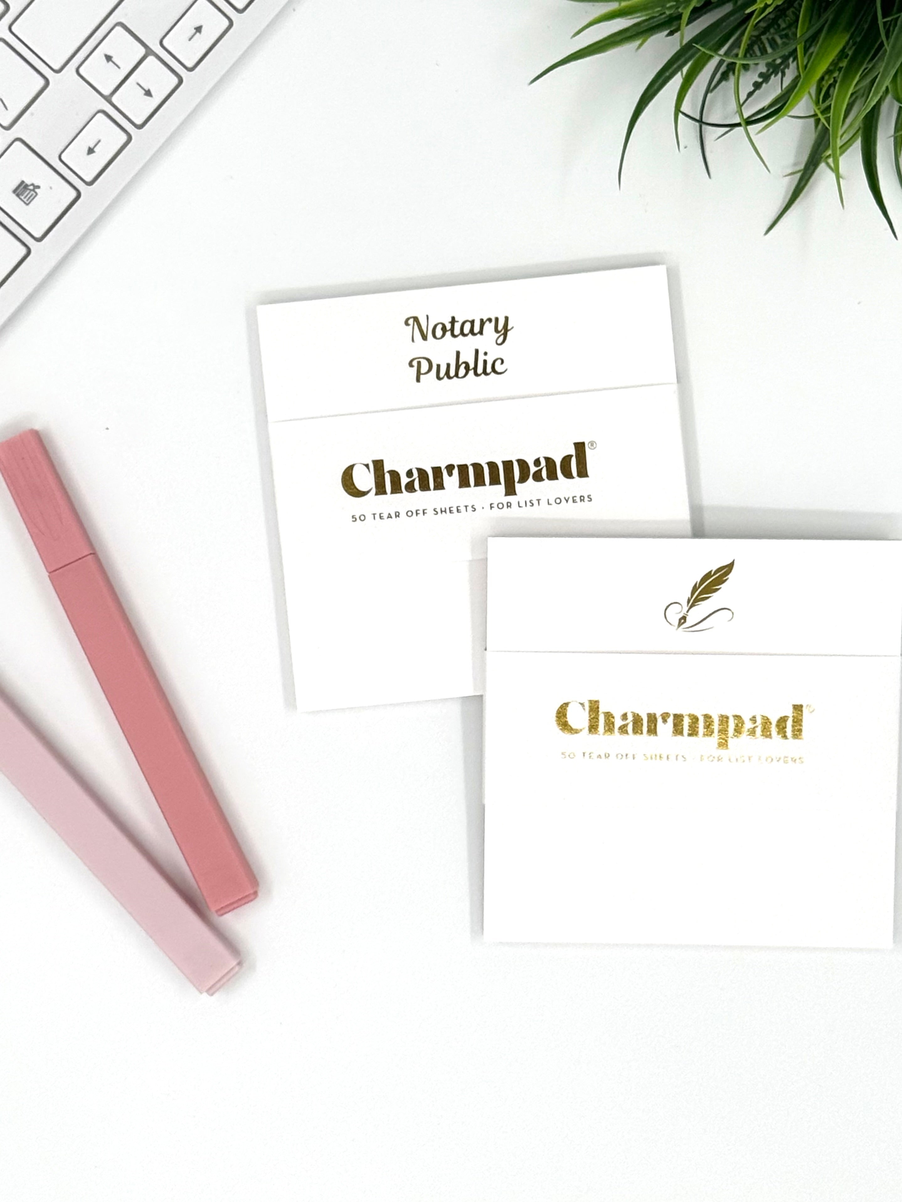 Charmpad notary public stationery on a white surface with a keyboard and plant.