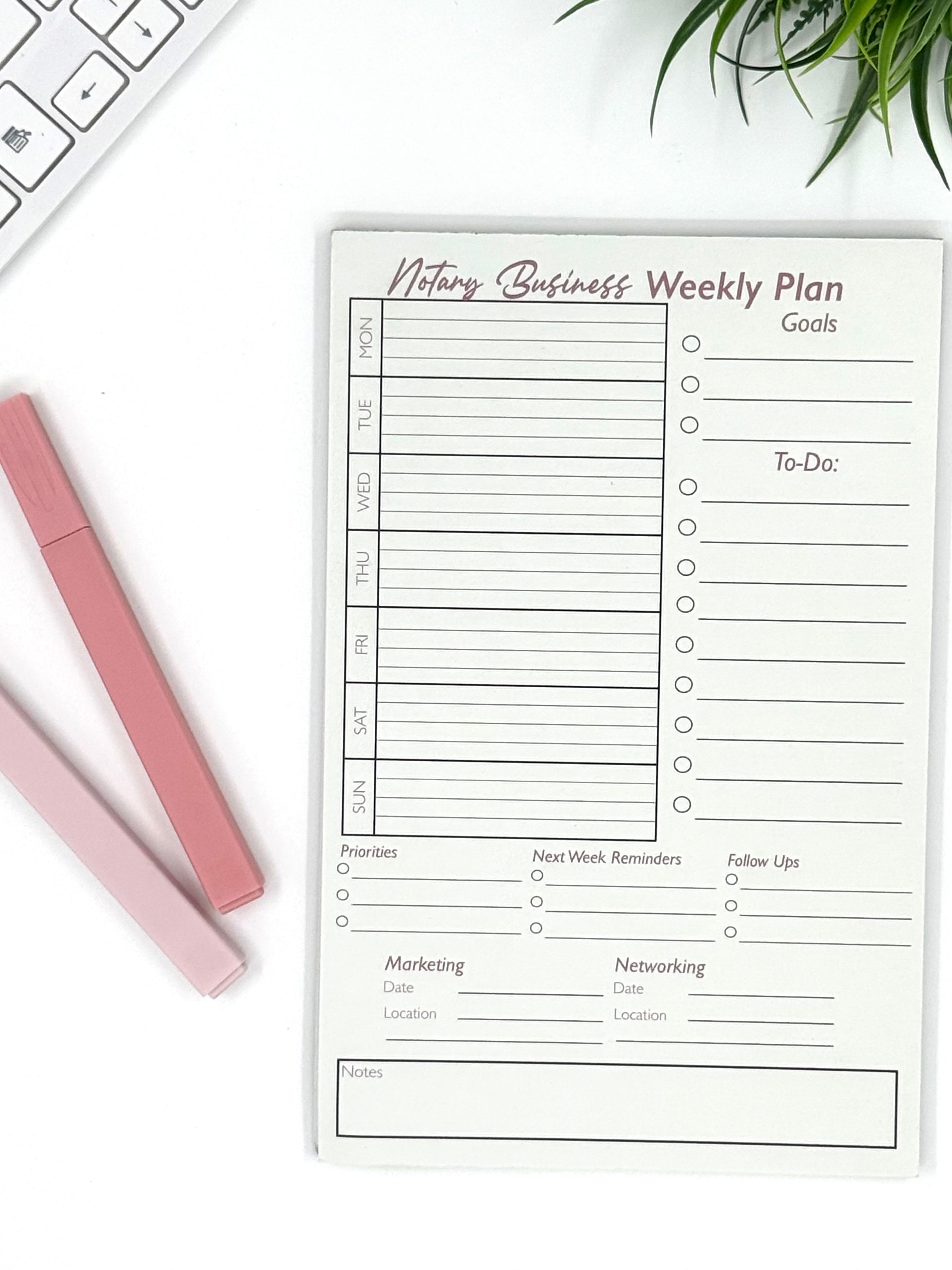 Weekly plan sheet for a business on a white surface with a pen and keyboard.