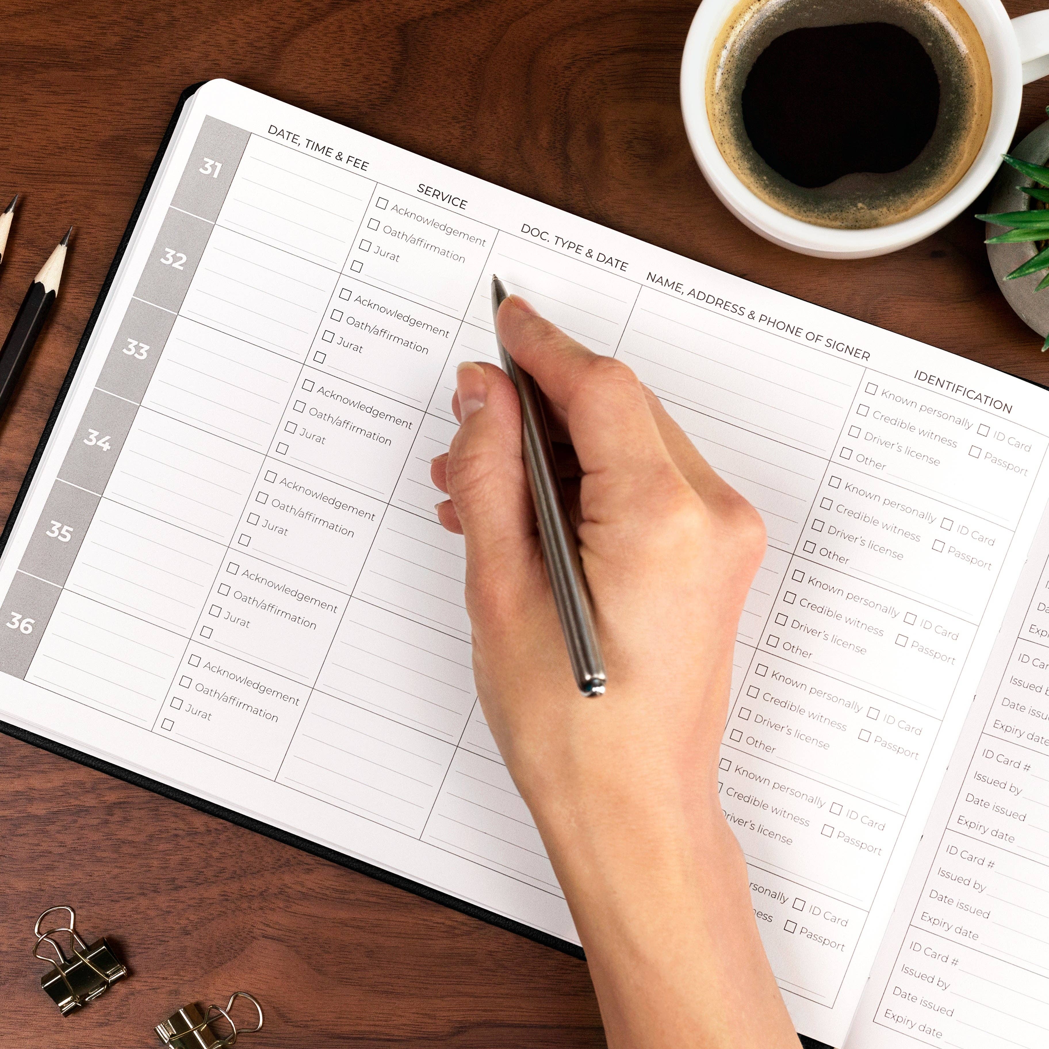 Hand filling out a form on a desk with a cup of coffee and office supplies.