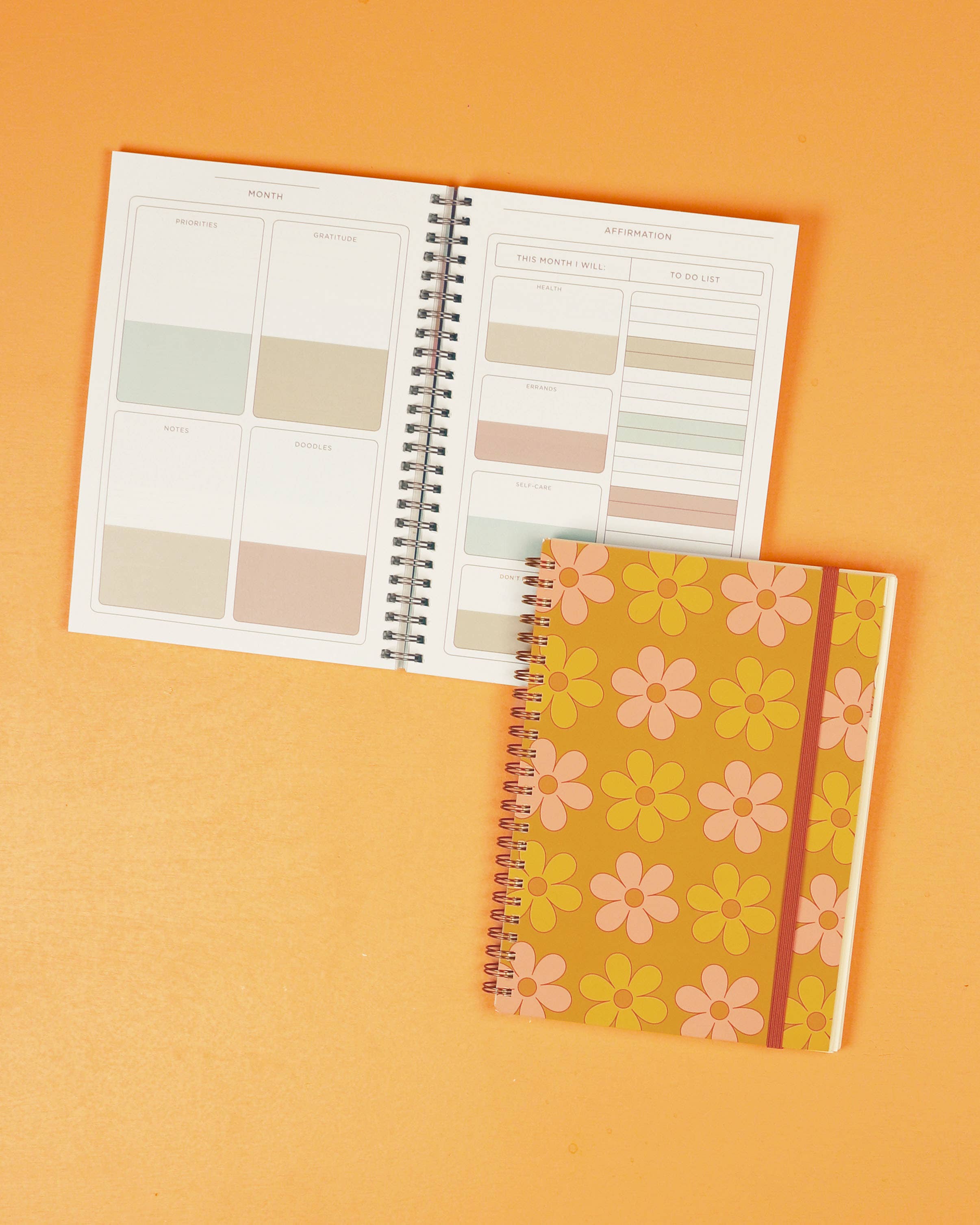 Spiral-bound notebook with a floral cover on an orange background